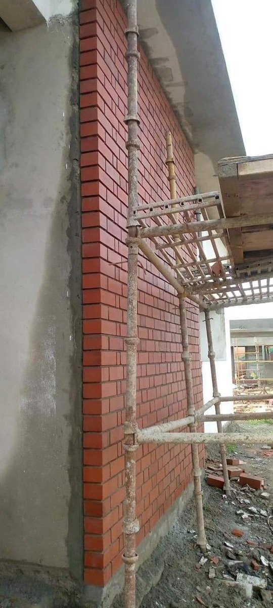 New exposed wire-cut brick wall beside scaffolding